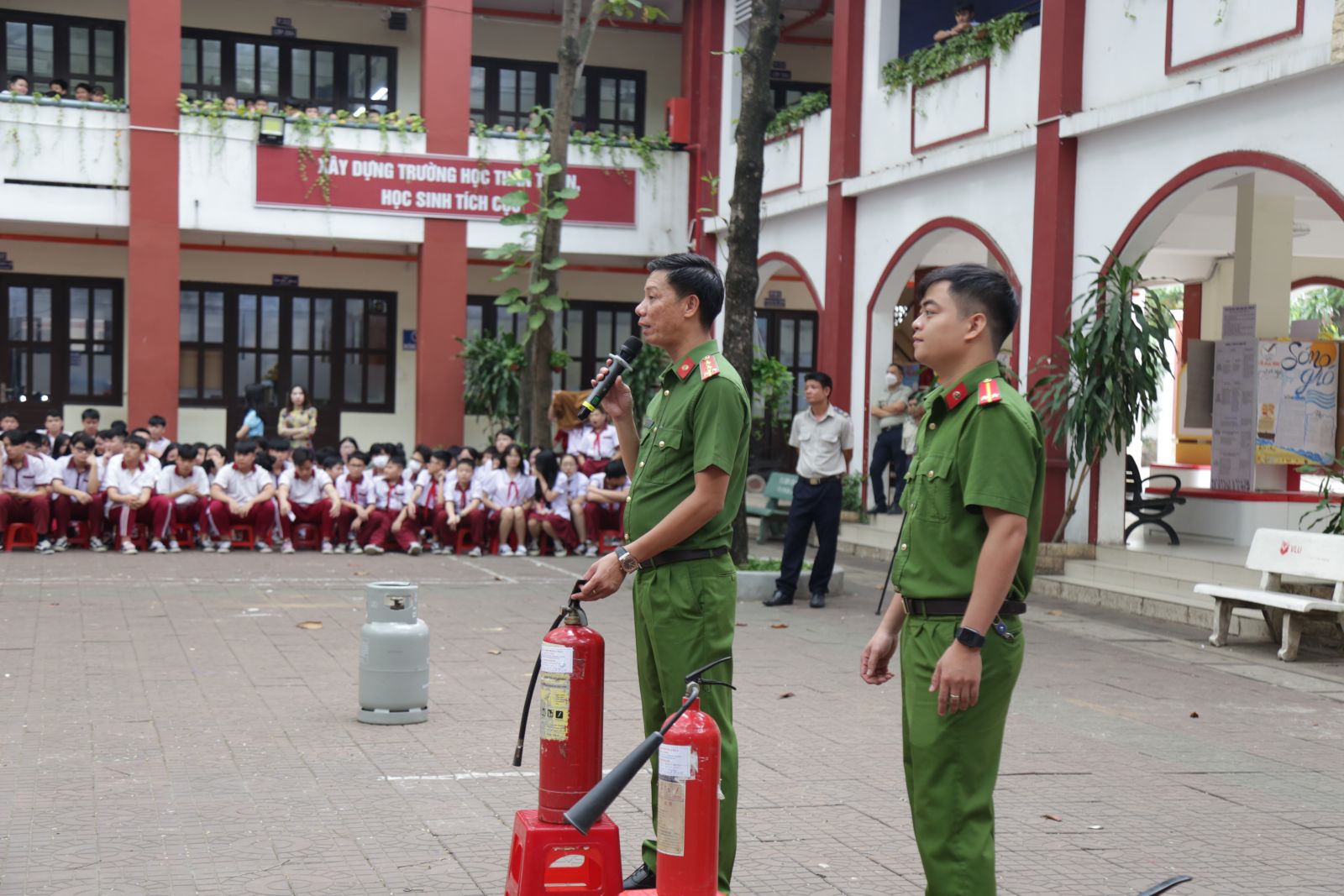 Đại úy Nguyễn Văn Hòa (trái) hướng dẫn sử dụng bình chữa cháy cho các em học sinh
